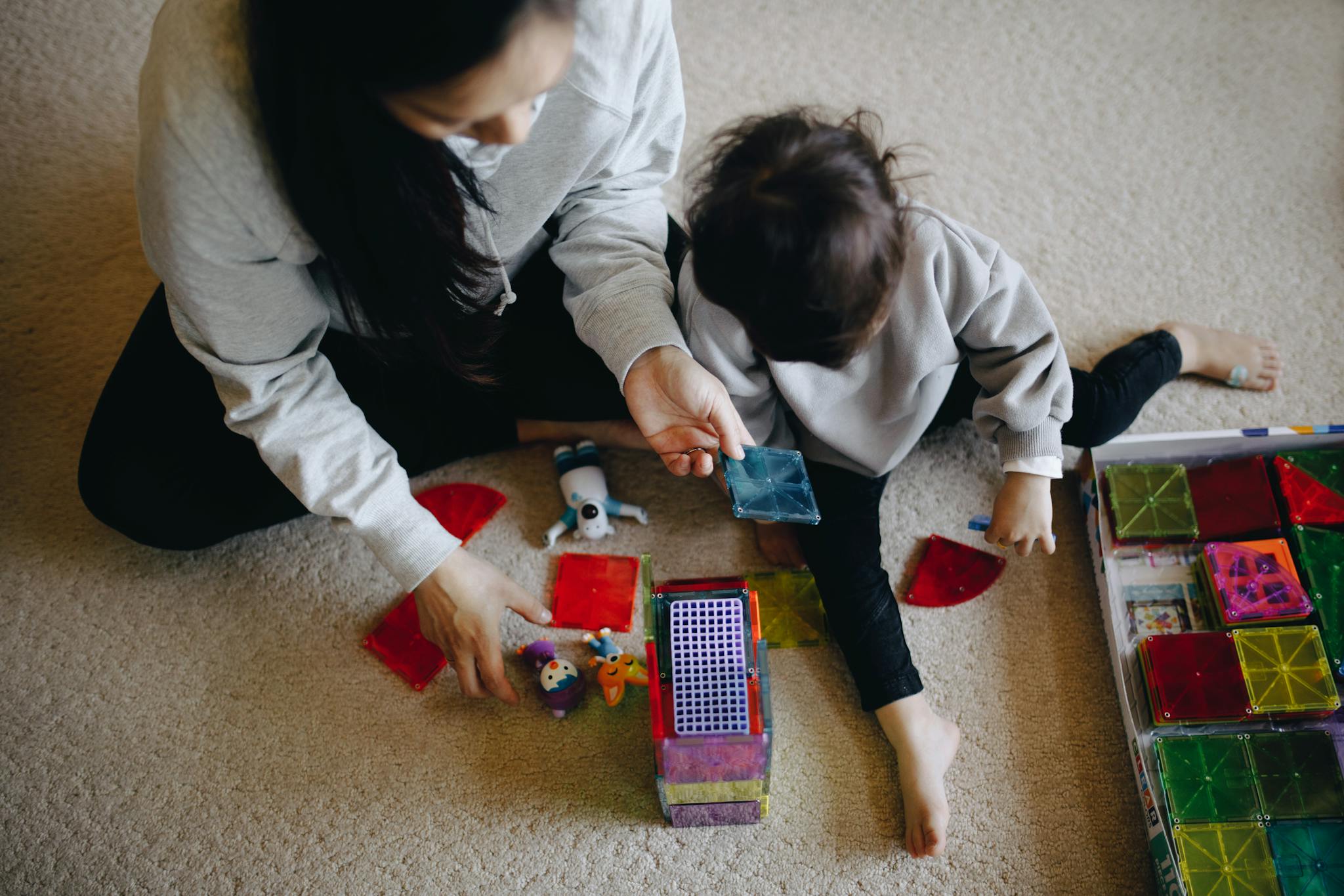 Mother and child engaged in a playful and educational activity with colorful blocks indoors.